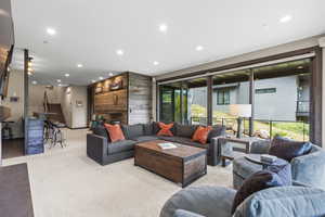 Living room featuring recessed lighting, wood walls, and light carpet