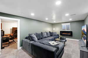 Spacious family room featuring a desk, light carpet, a glass covered fireplace, and recessed lighting