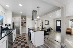 Kitchen featuring healthy amount of natural light, white cabinets, dark stone countertops, and a breakfast bar