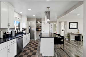 Kitchen with a kitchen bar, a center island, granite countertops, hanging light fixtures, and white cabinets