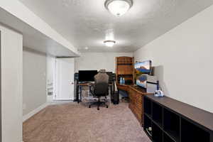 Bedroom (used as office) with light colored carpet and a textured ceiling
