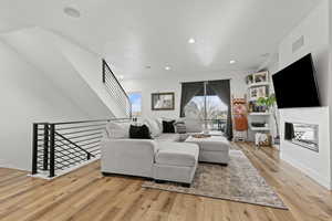 Living room featuring light wood-style flooring and a glass covered fireplace
