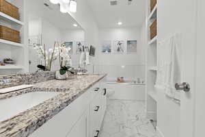 Full bath featuring a garden tub, double vanity, built in shelves, and recessed lighting