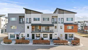 Rear view of property featuring stucco siding, a balcony, and a residential view
