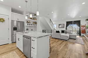 Kitchen featuring open shelves, white cabinetry, stainless steel appliances, a kitchen breakfast bar, and pendant lighting