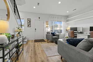 Living room with a desk, light wood finished floors, and recessed lighting
