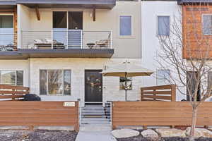 View of front of home featuring a balcony, a gate, brick siding, and a fenced front yard