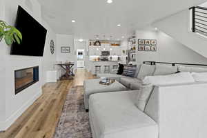 Living room with a glass covered fireplace, light wood finished floors, and recessed lighting