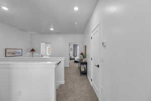 Corridor with light carpet, recessed lighting, and an upstairs landing