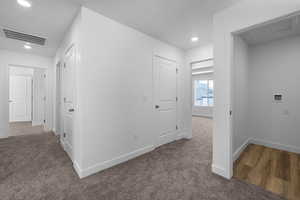 Corridor with dark colored carpet and recessed lighting