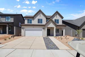 View of front of house with stucco siding, driveway, an attached garage, and covered porch