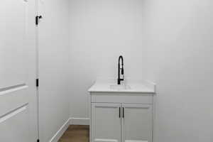Laundry area with dark wood-style flooring and a sink