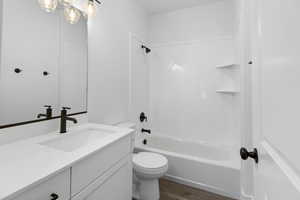 Full bathroom featuring shower / bath combination, vanity, and dark wood-style floors