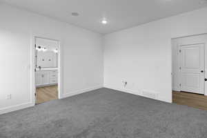 Unfurnished bedroom featuring light carpet and connected bathroom