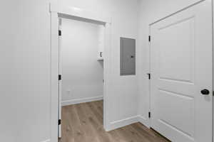 Hallway with electric panel and light wood-style floors