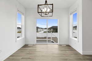 Unfurnished dining area featuring light wood-type flooring and a chandelier