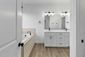 Bathroom with double vanity, a garden tub, and light wood-style flooring