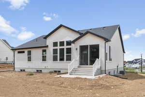 Back of property with entry steps, a shingled roof, and stucco siding