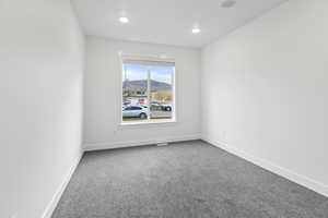 Empty room featuring a mountain view and light carpet