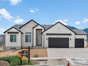 Modern farmhouse with a mountain view, board and batten siding, an attached garage, and concrete driveway