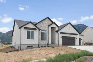 Modern farmhouse style home featuring a mountain view, board and batten siding, an attached garage, and driveway