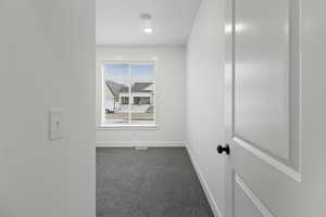 Spare room featuring dark colored carpet and baseboards