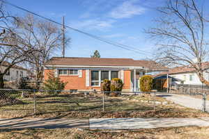 View of front of house featuring brick siding, an attached carport, driveway, and a fenced front yard