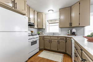 Kitchen featuring white appliances, light countertops, and dark wood finished floors