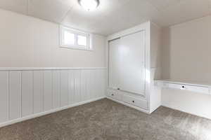 Unfurnished bedroom featuring a wainscoted wall, carpet floors, and a closet