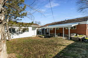 Back of property featuring a patio, a yard, brick siding, and a garden