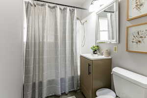 Bathroom featuring vanity, shower / bath combo with shower curtain, and dark wood-style floors
