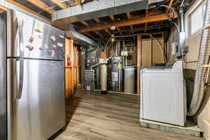 Below grade area with freestanding refrigerator, washer / clothes dryer, strapped water heater, heating unit, and electric panel