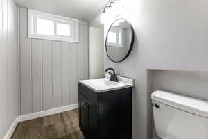 Half bath featuring vanity and dark wood-type flooring