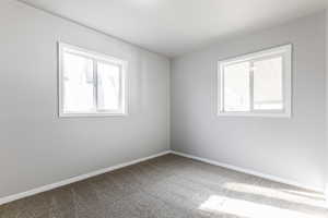 Carpeted spare room featuring baseboards