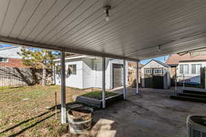 Fenced backyard featuring a storage unit and a patio area