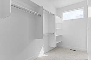 Walk in closet with light colored carpet