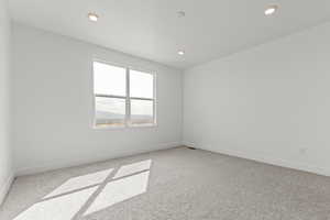 Empty room with light carpet and recessed lighting