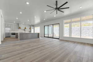 Unfurnished living room featuring light wood-style flooring, a ceiling fan, and recessed lighting