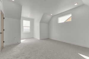Additional living space with vaulted ceiling, light colored carpet, and recessed lighting