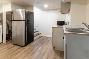 Kitchen with freestanding refrigerator, light countertops, light wood-style floors, a textured ceiling, and washer / clothes dryer