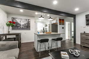 Kitchen featuring white cabinets, pendant lighting, dark wood-type flooring, beamed ceiling, and a breakfast bar