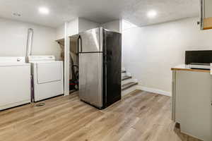 Laundry area featuring light wood-style floors, a textured ceiling, washer and dryer, and recessed lighting