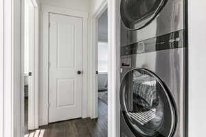 Laundry area with stacked washer and dryer and dark wood-style floors