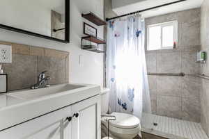 Full bathroom featuring vanity, a tile shower, and tasteful backsplash