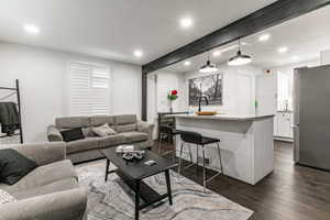 Living area with dark wood finished floors, beam ceiling, and recessed lighting