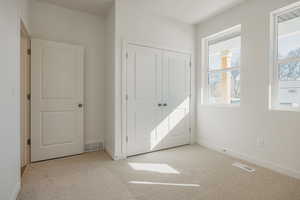 Unfurnished bedroom with light carpet and a closet