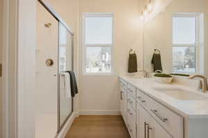 Bathroom featuring double vanity, a shower stall, and light wood-type flooring