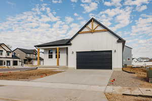 Modern farmhouse style home with board and batten siding, an attached garage, concrete driveway, a residential view, and covered porch