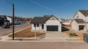 Modern farmhouse style home with a residential view, board and batten siding, concrete driveway, and covered porch