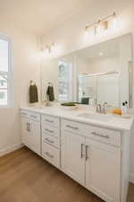 Bathroom featuring double vanity, a shower stall, and light wood-style floors